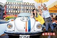 她在大雨中仍得擺出美美的姿勢，工作人員忙為她撐傘。